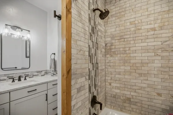 a bathroom with a granite countertop sink a mirror and shower