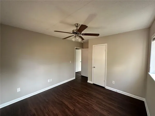 a view of an empty room with a ceiling fan and wooden floor