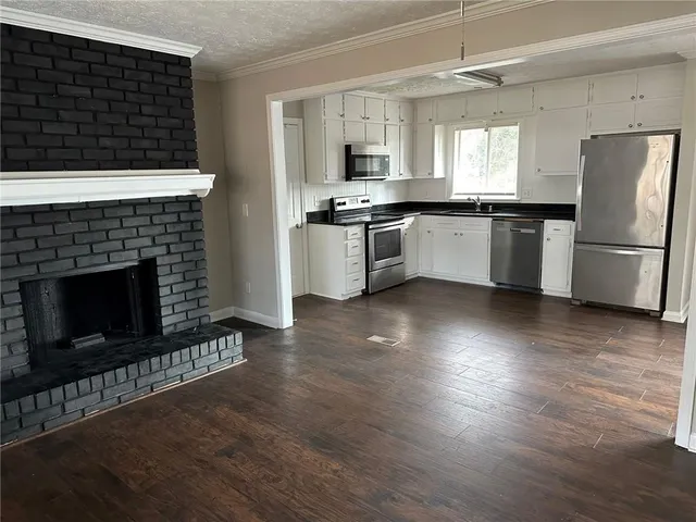 a kitchen with granite countertop a stove a refrigerator and a fireplace