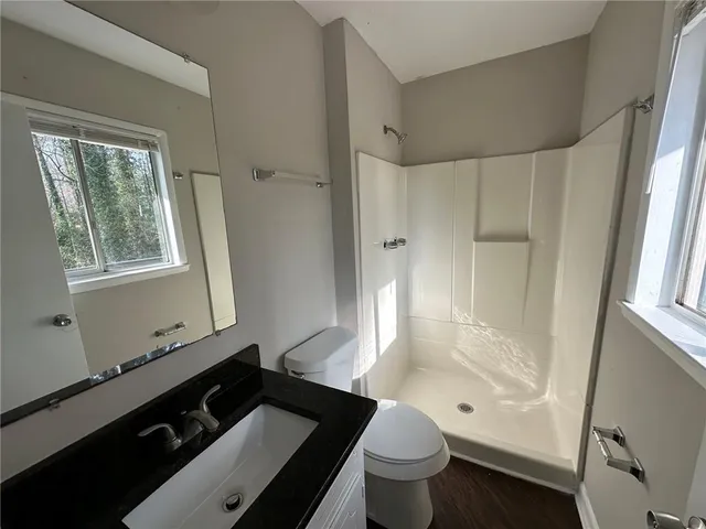 a bathroom with a granite countertop sink toilet a mirror and shower