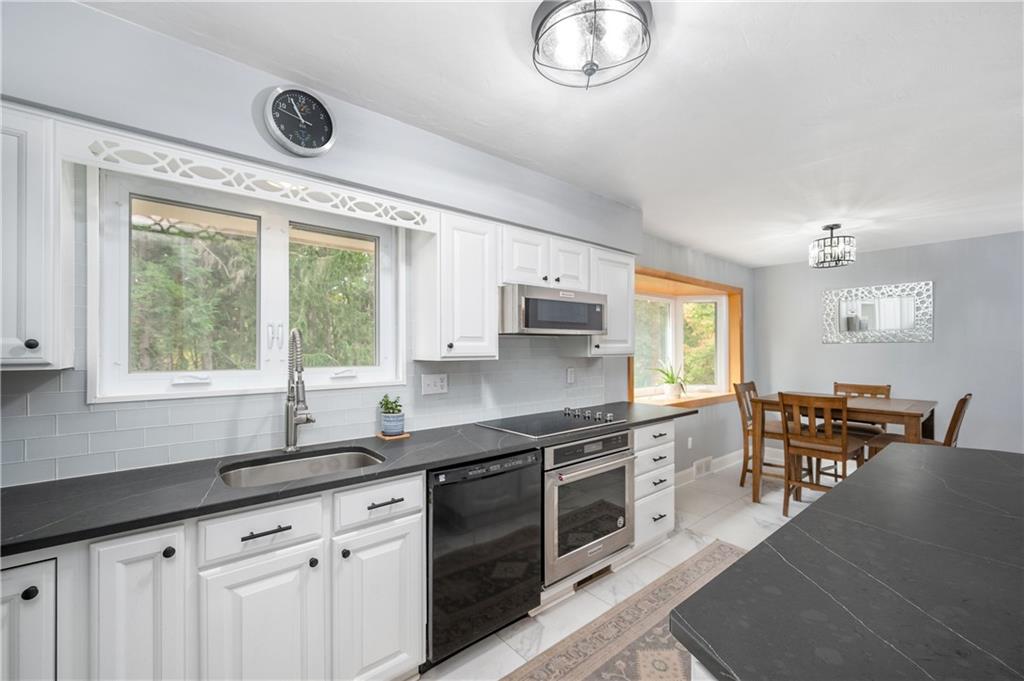 424 Brooks Road Wexford, PA 15090 - Photo 13 of 46 a kitchen with stainless steel appliances granite countertop a sink dishwasher a stove a dining table and chairs with wooden floor
