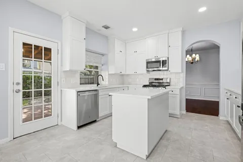a kitchen with white cabinets and appliances