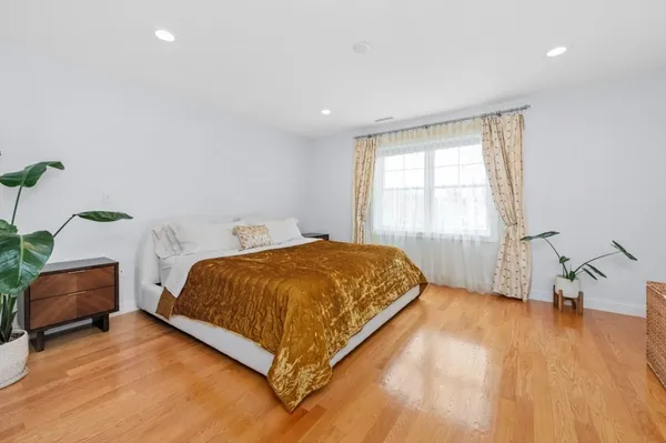 a spacious bedroom with a bed and wooden floor