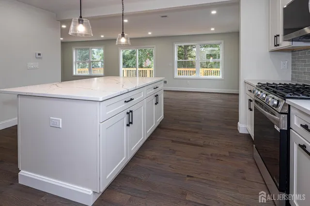 a kitchen with stainless steel appliances granite countertop wooden floors and white cabinets