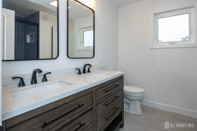 a bathroom with sink a toilet a mirror and window