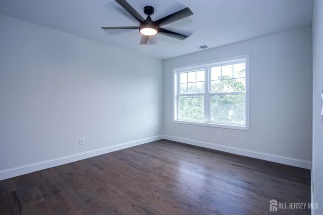 an empty room with wooden floor fan and windows