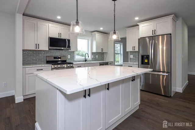 a kitchen with stainless steel appliances a sink a stove a refrigerator and cabinets