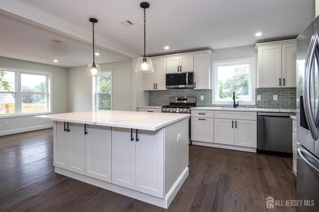 a kitchen with stainless steel appliances a sink a stove a microwave a center island and wooden floor