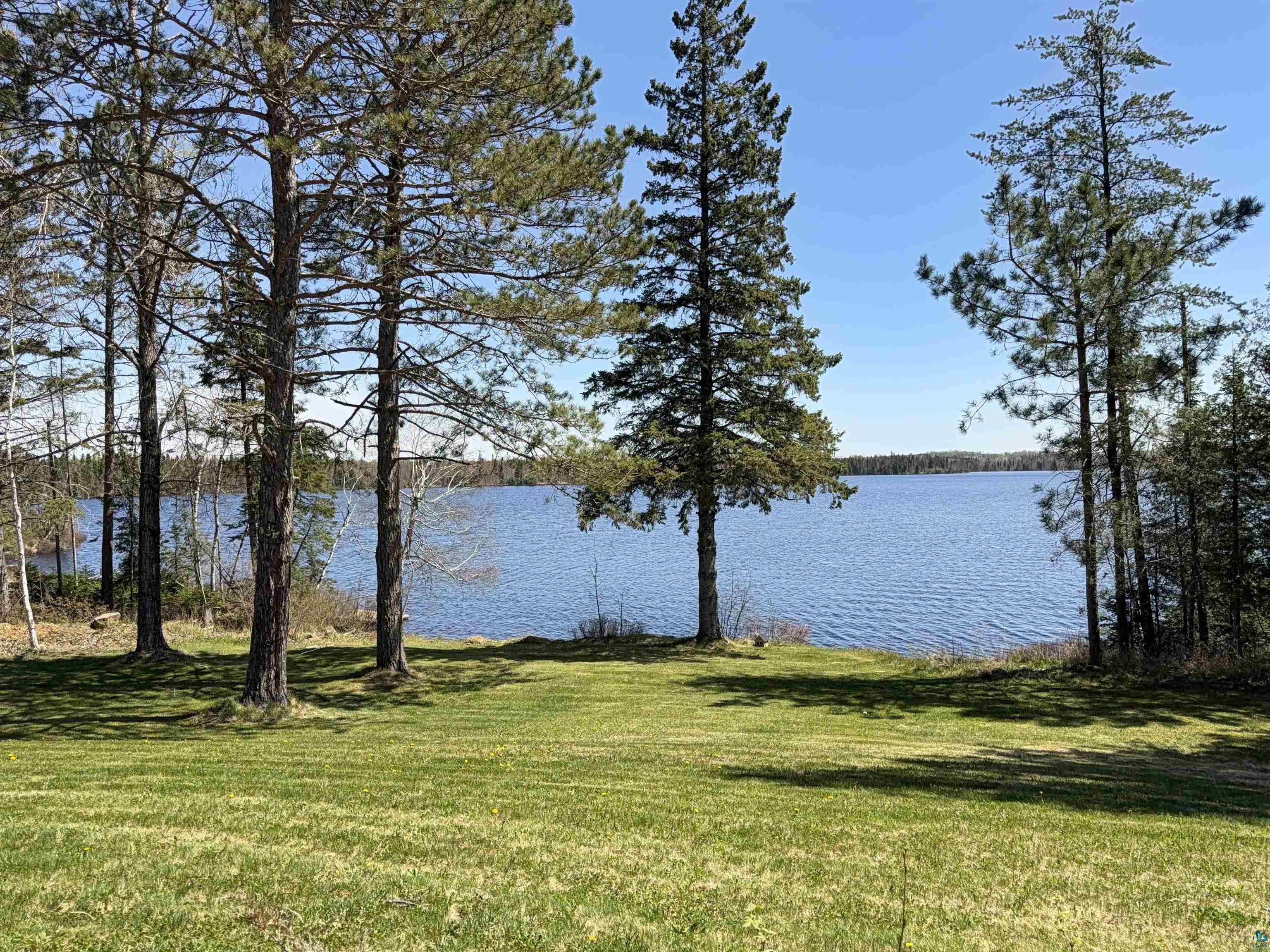5274 Marble Lake Road Two Harbors, MN 55616 - Photo 60 of 79 Expansive lakefront property featuring a broad body of water, mature evergreen trees, lush green lawn, and additional natural foliage