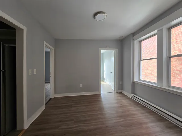 a view of an empty room with wooden floor and a window