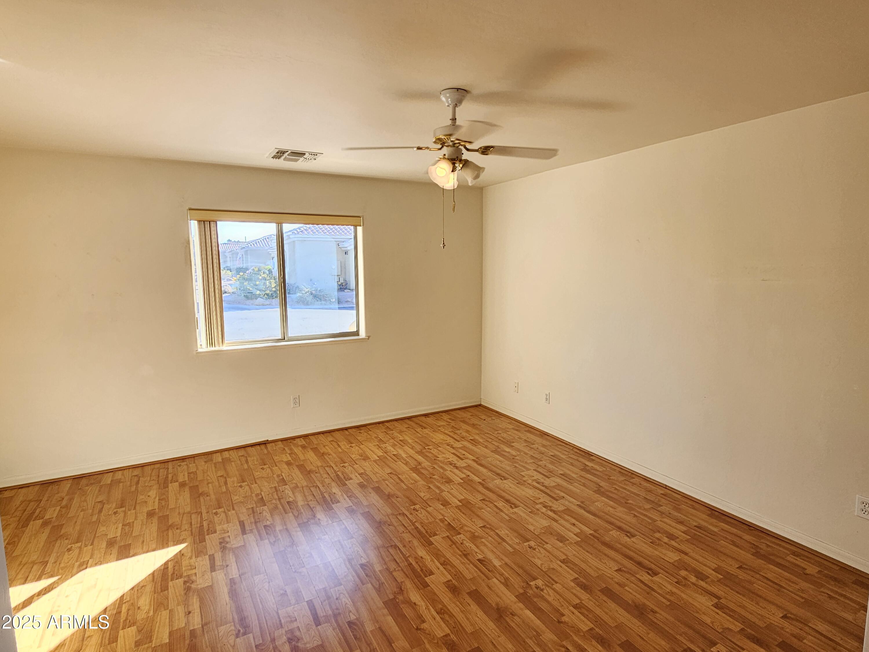 5830 East McKellips Road, Unit 139 Mesa, AZ 85215 - Photo 24 of 53 an empty room with wooden floor ceiling fan and windows
