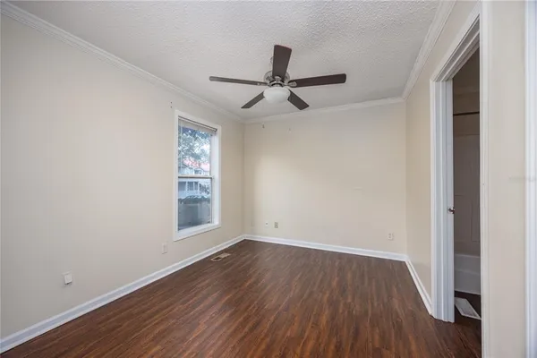 an empty room with wooden floor ceiling fan and windows
