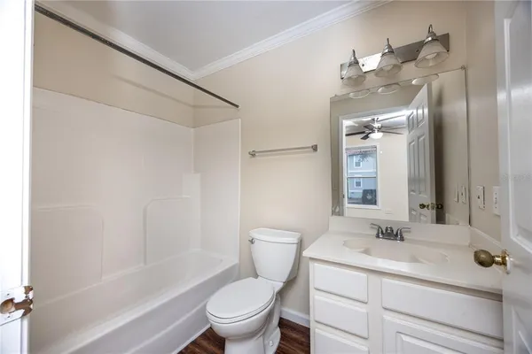 a bathroom with a toilet a sink a mirror a shower a vanity and window