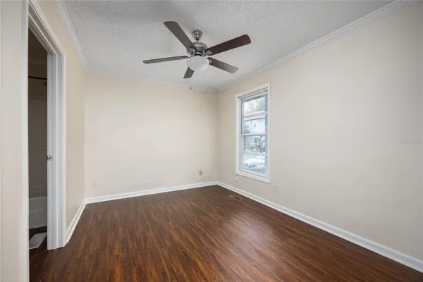 an empty room with wooden floor ceiling fan and windows