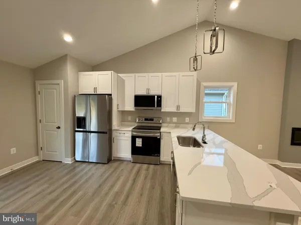 a large kitchen with a stove a sink dishwasher a refrigerator and a oven with wooden floor