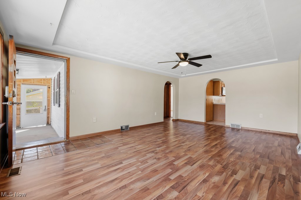 1702 Far View Road Akron, OH 44312 - Photo 6 of 49 Unfurnished living room with light wood-style flooring, a raised ceiling, a ceiling fan, and arched walkways