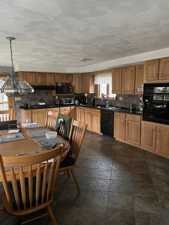 54 Charme Road Billerica, MA 01821 - Photo 5 of 23 a kitchen with a table chairs microwave and cabinets