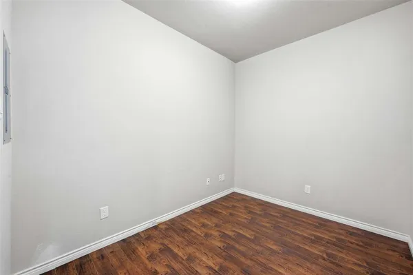 a view of an empty room with wooden floor and white wall