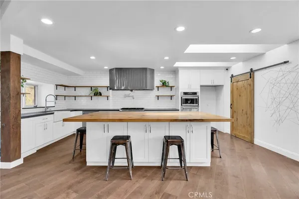 a kitchen with stainless steel appliances kitchen island granite countertop a table chairs sink and cabinets