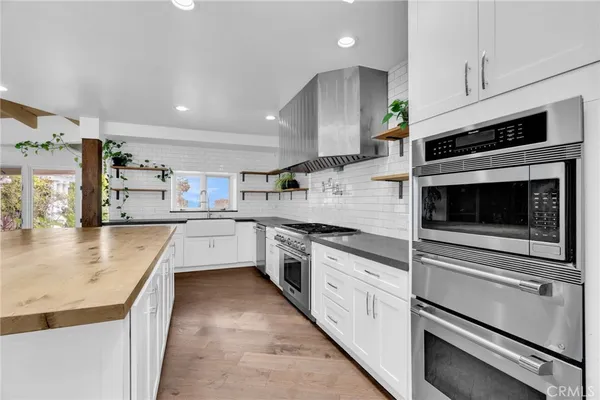 a dining hall with stainless steel appliances granite countertop a stove top oven a dining table and chairs with wooden floor