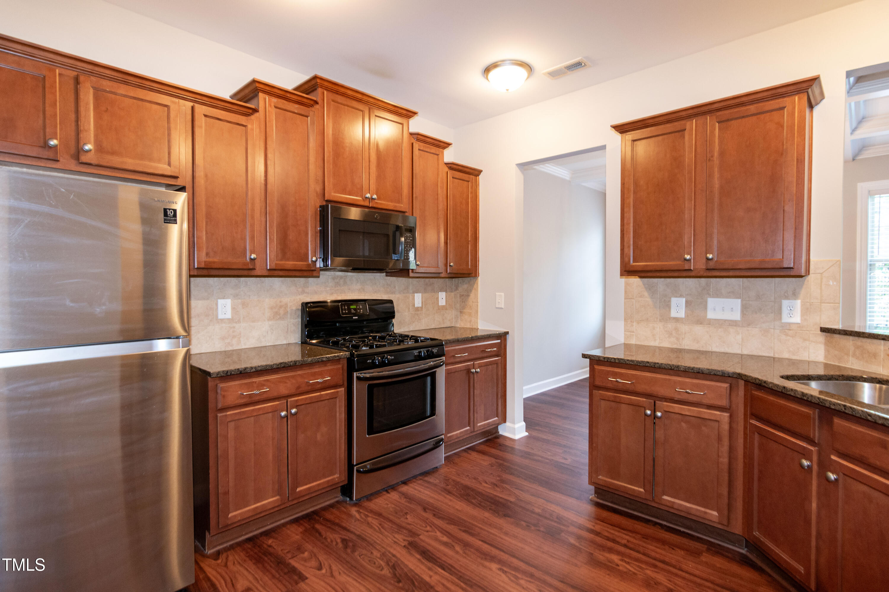 206 Roundhouse Lane Morrisville, NC 27560 - Photo 10 of 42 a kitchen with stainless steel appliances wooden cabinets a stove a sink and a microwave