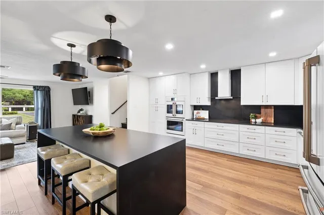 a kitchen with stainless steel appliances kitchen island granite countertop a stove a sink a dining table and chairs with wooden floor