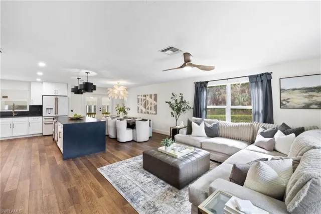 a living room with furniture kitchen view and a large window