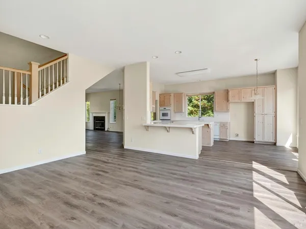 a view of an empty room with wooden floor and fan