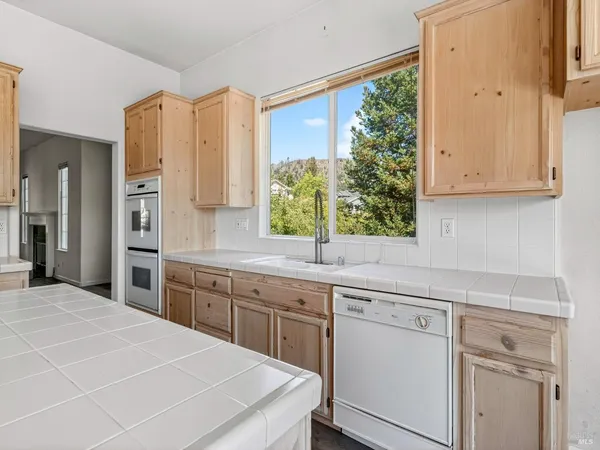 a kitchen with a sink a window a counter top space stainless steel appliances and cabinets