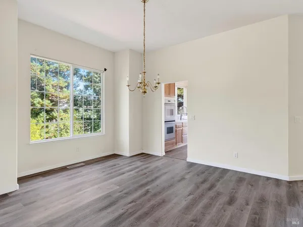 an empty room with wooden floor fireplace and windows