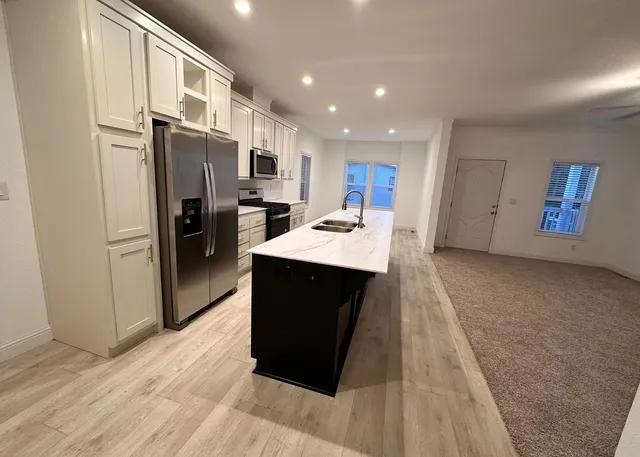 a kitchen with stainless steel appliances kitchen island granite countertop a refrigerator stove and oven