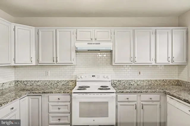a kitchen with granite countertop white cabinets and white appliances