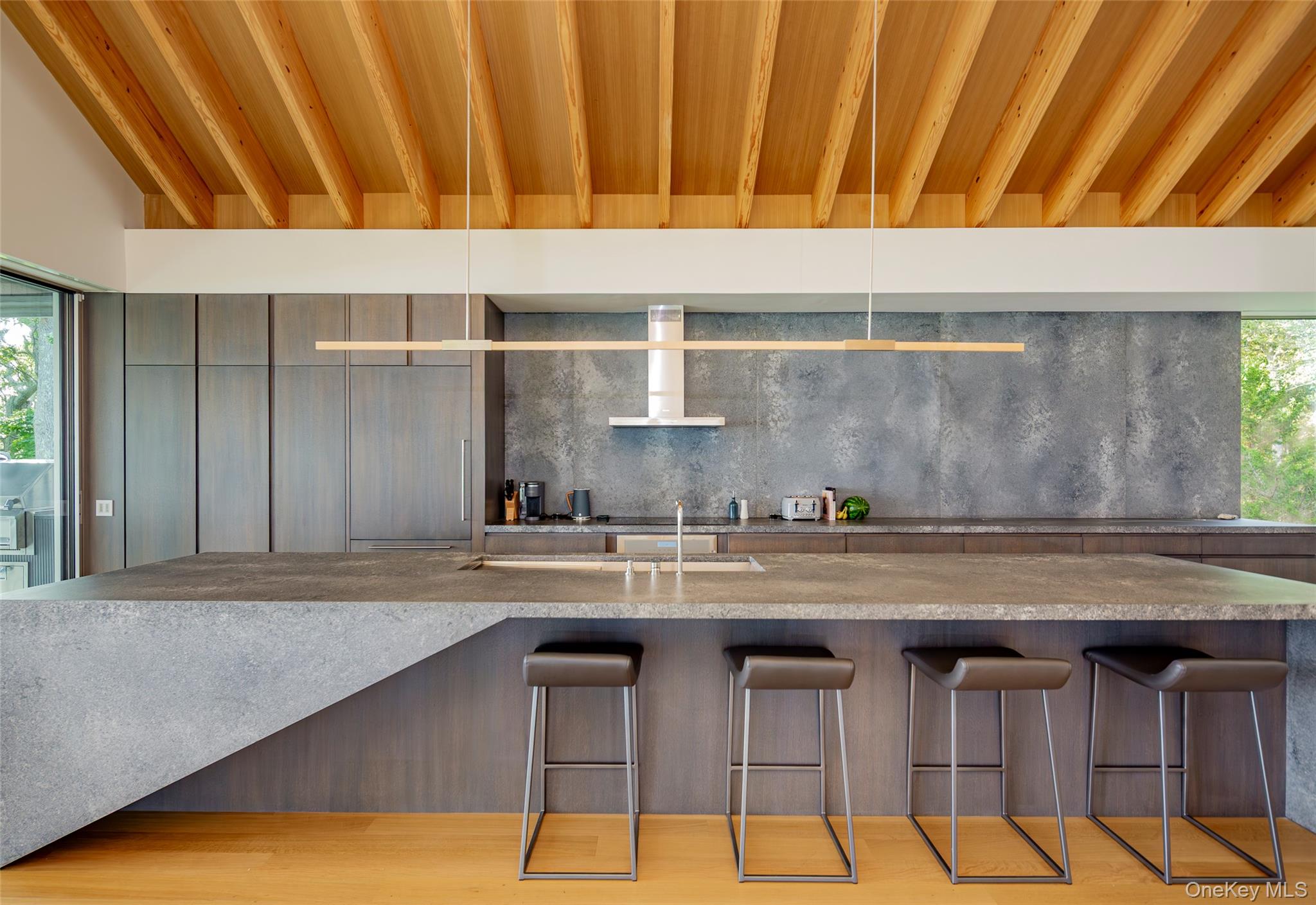 47 L South Ferry Road Shelter Island, NY 11964 - Photo 12 of 35 Kitchen with modern cabinets, wall chimney exhaust hood, decorative backsplash, and light stone countertops