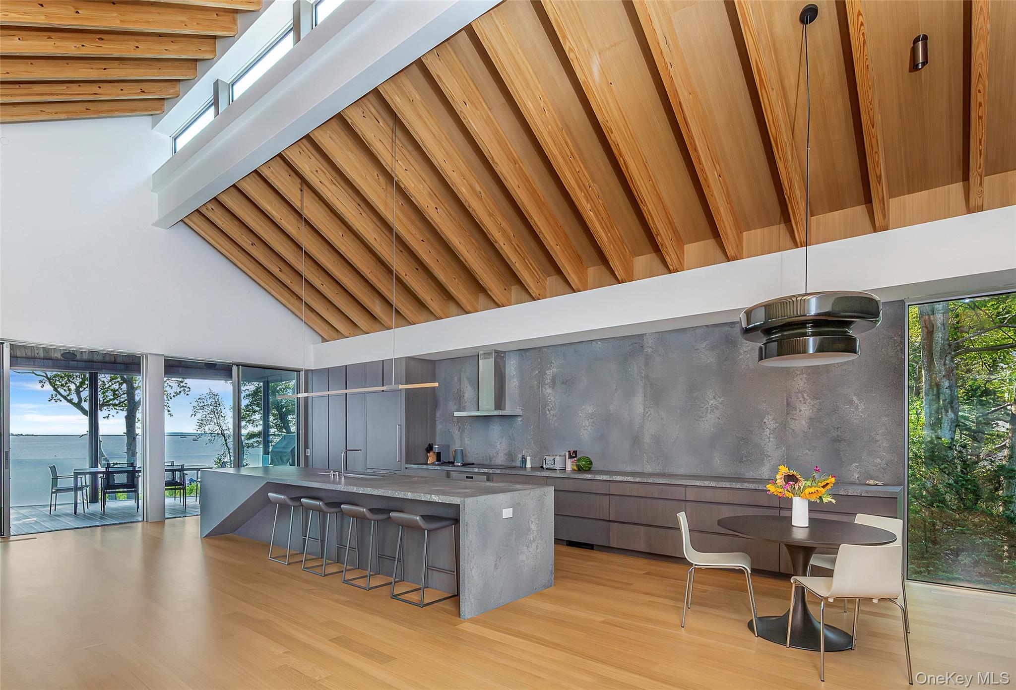47 L South Ferry Road Shelter Island, NY 11964 - Photo 14 of 35 Kitchen with modern cabinets, high vaulted ceiling, a kitchen bar, light stone countertops, and light wood finished floors