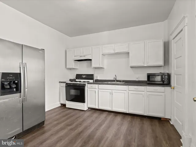 a kitchen with granite countertop white cabinets and stainless steel appliances