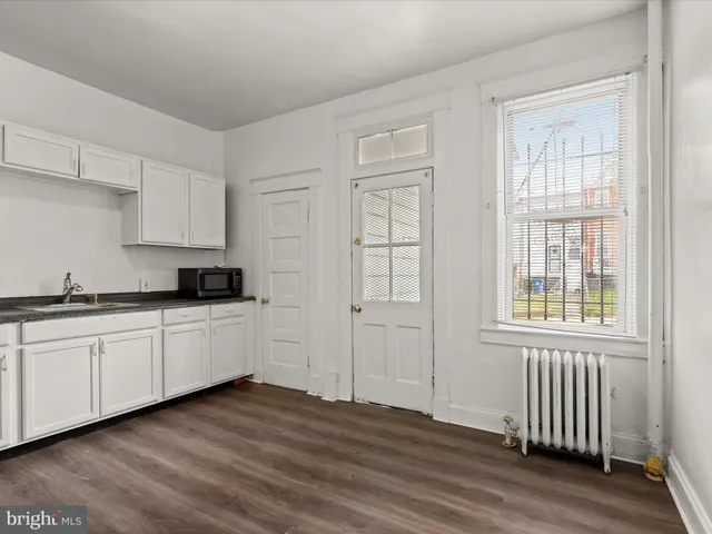 a kitchen with wooden floors and white cabinets
