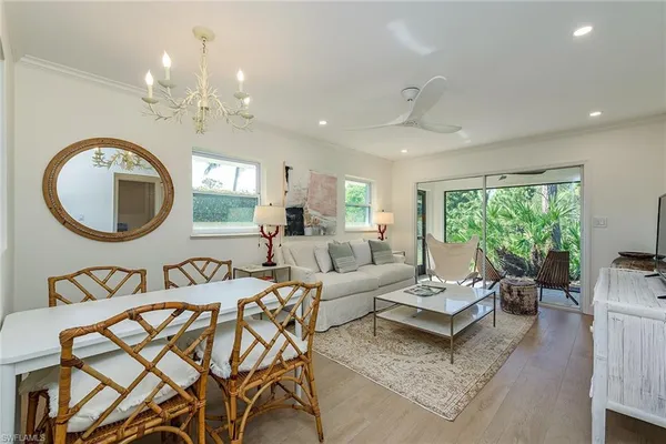 a living room with a couch a dining table a lamp and a large window