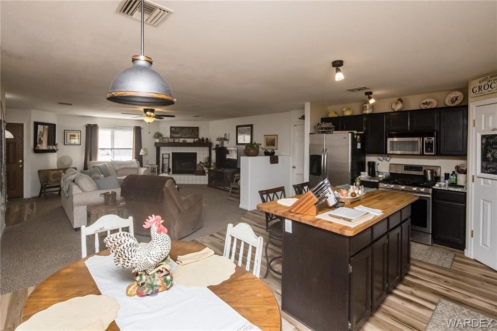 2333 Primavera Loop Fort Mohave, AZ 86426 - Photo 21 of 57 a kitchen with stainless steel appliances granite countertop a stove top oven a sink dishwasher a dining table and chairs with wooden floor