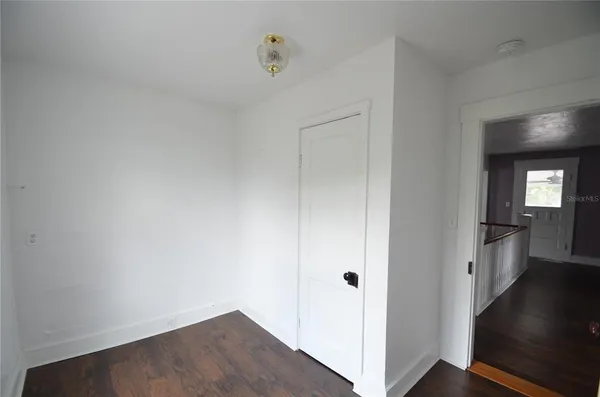 an empty room with wooden floor chandelier fan and windows