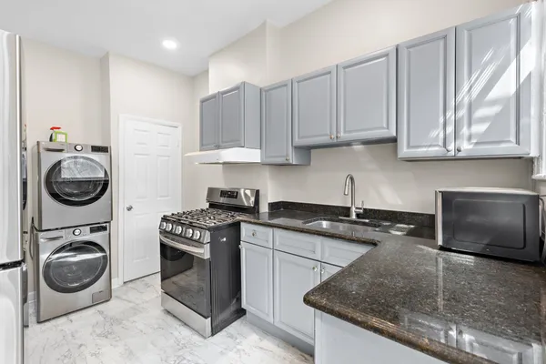 a kitchen with granite countertop white cabinets and a stove top oven