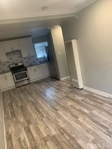 a view of an empty room with wooden floor and fan