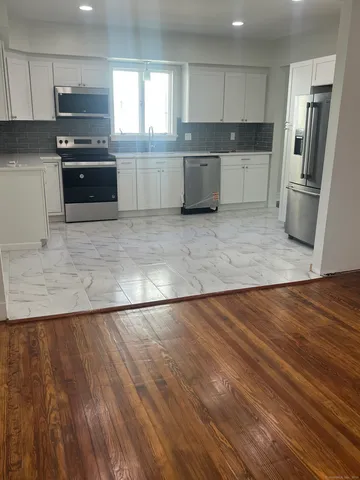 a large kitchen with a wooden floor and stainless steel appliances