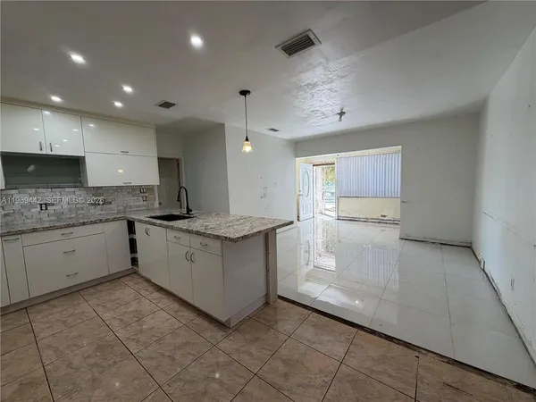 a large white kitchen with center island and stainless steel appliances