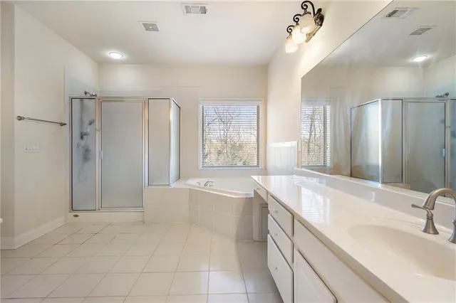 a spacious bathroom with a tub sink shower and mirror