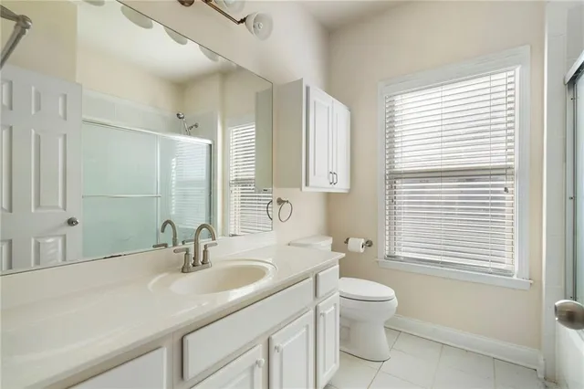 a bathroom with a toilet a sink a mirror and a window