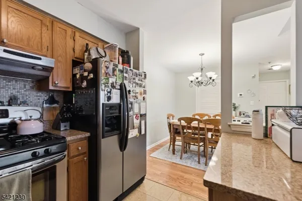 a kitchen with stainless steel appliances granite countertop a stove a refrigerator and wooden cabinets