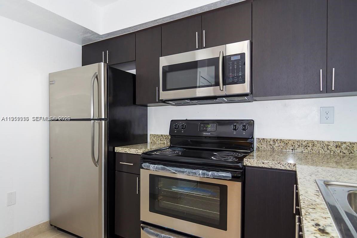 11750 Southwest 18th Street, Unit 1221 Miami, FL 33175 - Photo 4 of 6 a kitchen with stainless steel appliances a stove a microwave and a refrigerator