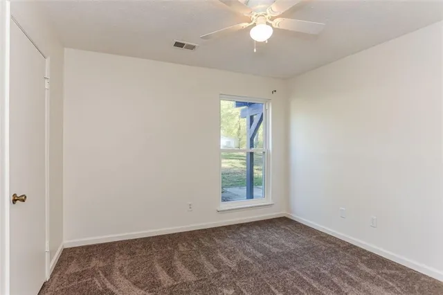 an empty room with windows and fan