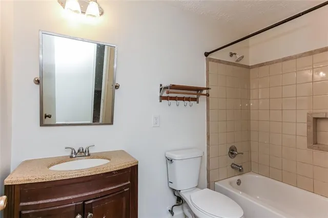 a bathroom with a granite countertop sink toilet a mirror and shower