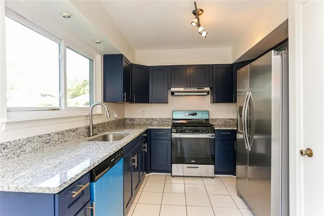 a kitchen with stainless steel appliances granite countertop a sink stove and refrigerator